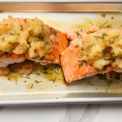 Crab and shrimp stuffed salmon baked to golden perfection in a ceramic dish